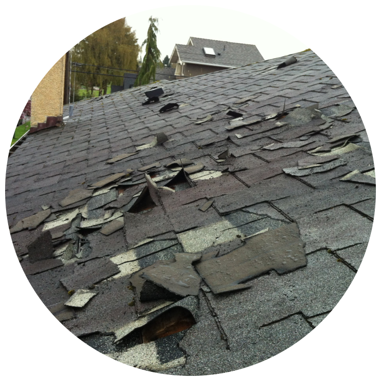 Severely damaged asphalt shingle roof with missing and broken shingles needing repair